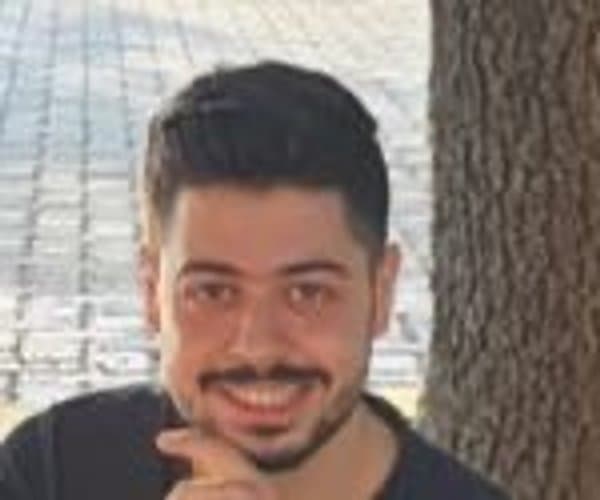 Doumit smiling next to a tree
