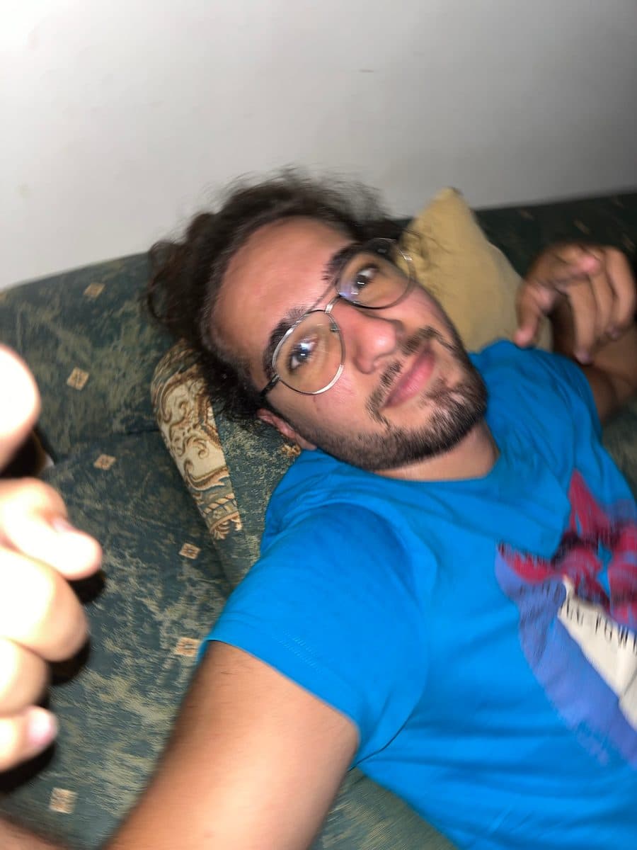 Blurry selfie of Patrick lying on a couch giving a thumbs up
