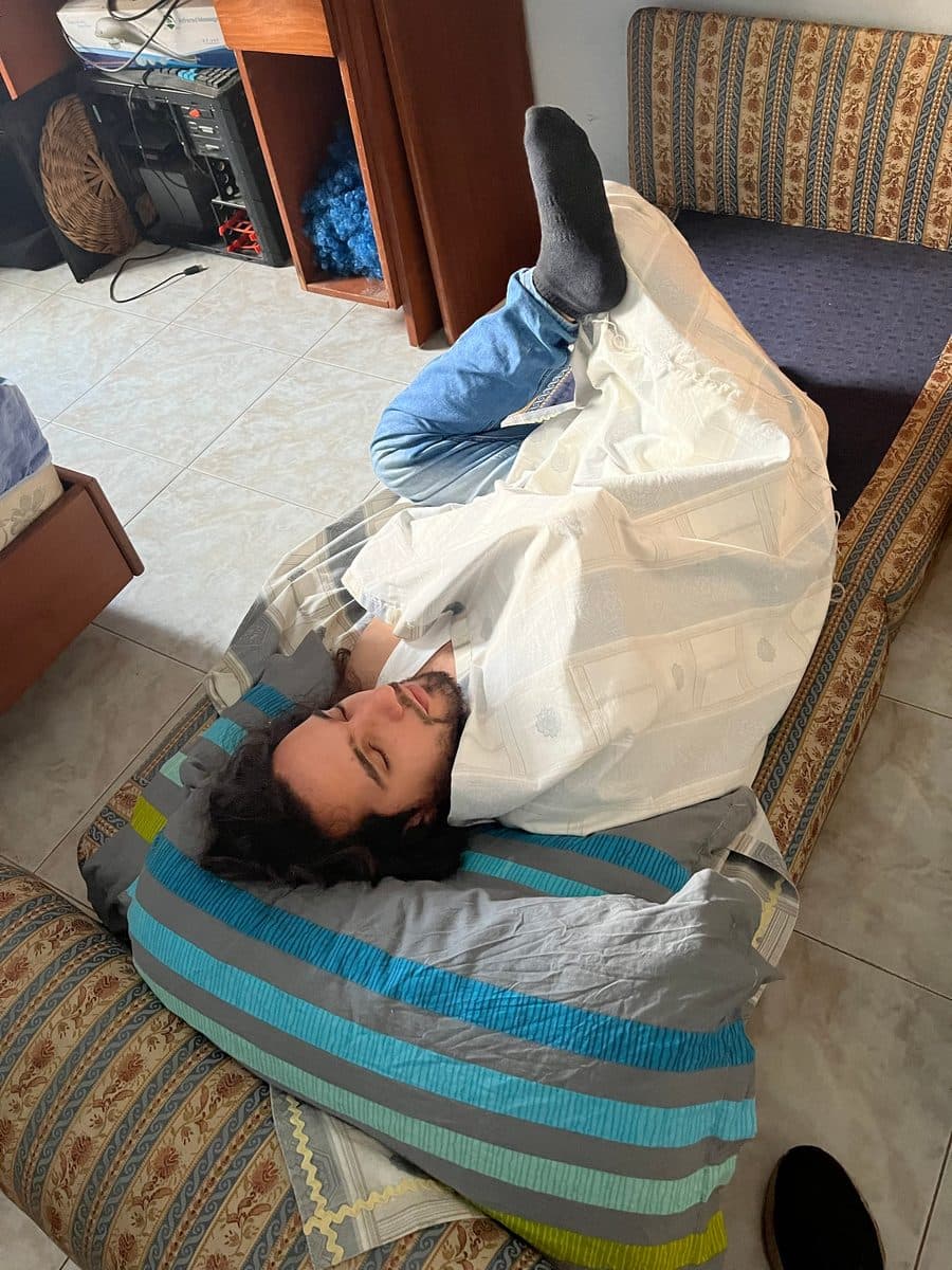 Patrick asleep on a mattress on the floor with one leg propped up